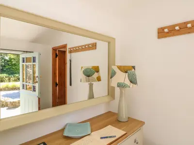 a mirror on top of a wooden desk with a vase at Pond Cottage in Truro