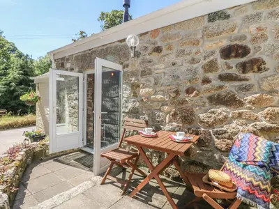 a stone cottage with a table and chairs on the patio at Pond Cottage in Truro