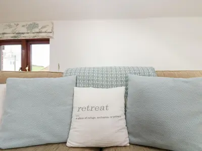 a couch with two pillows with a retreat sign on it at Castle Dore Barn in Par