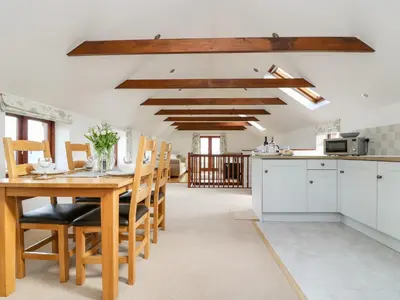 a kitchen and dining room with a wooden table and chairs at Castle Dore Barn in Par