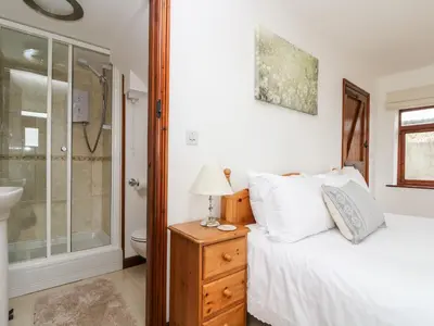 a bedroom with a bed and a bathroom with a shower at Castle Dore Barn in Par