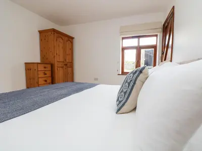 a bedroom with a white bed with a pillow on it at Castle Dore Barn in Par