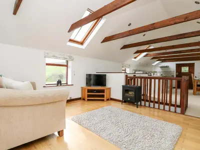 a living room with a couch and a television at Castle Dore Barn in Par