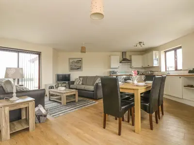 a kitchen and living room with a table and chairs at Sea Spray in Marazion