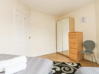 a bedroom with a bed and a mirror and a chair at Sea Spray in Marazion