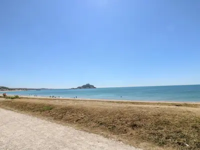 a sandy beach with people in the water at Sea Spray in Marazion
