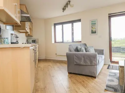 a living room with a couch and a kitchen at Sea Horses in Marazion