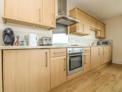 a kitchen with wooden cabinets and stainless steel appliances at Sea Horses in Marazion