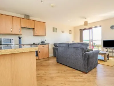 a living room with a couch and a kitchen at Surfside in Marazion