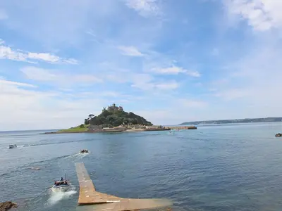 a small island in the water with a small boat at Surfside in Marazion