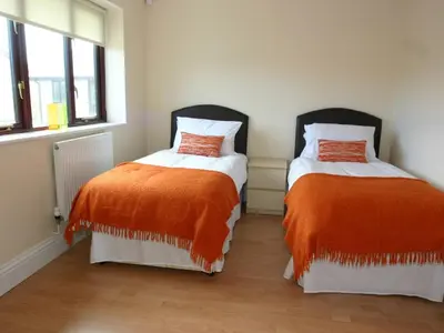 two beds with orange and white sheets in a room at Sea Shore in Marazion