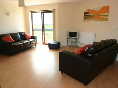 a living room with two leather couches and a television at Sea Shore in Marazion
