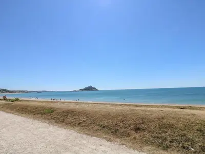 a sandy beach with people in the water at Sea Shore in Marazion
