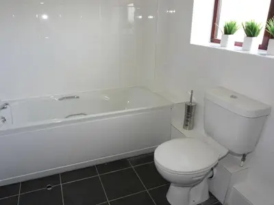 a white bathroom with a toilet and a bath tub at Sea Shore in Marazion