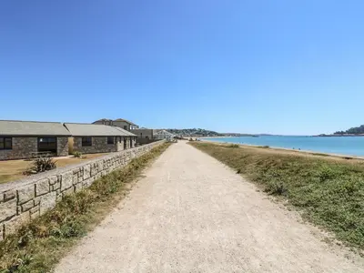 a dirt road next to a building and the water at Seashells in Marazion