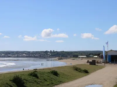 a beach with people on the sand and water at Seashells in Marazion