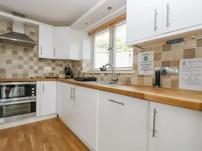a kitchen with white cabinets and a sink at Rock Pool in Downderry