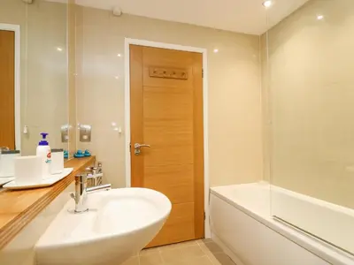 a bathroom with a sink and a tub and a toilet at Rock Pool in Downderry