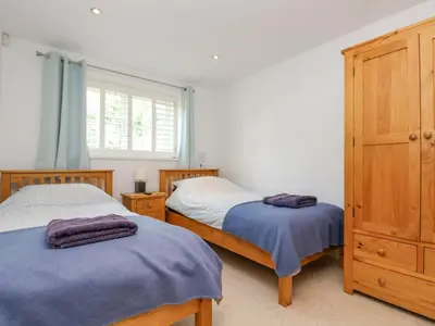 a bedroom with two beds and a wooden cabinet at Rock Pool in Downderry