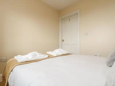 a bedroom with a white bed with two towels on it at Shoreline in Marazion