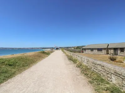 a dirt road next to a retaining wall next to the water at Shoreline in Marazion