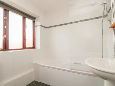 a white bathroom with a tub and a sink at Shoreline in Marazion