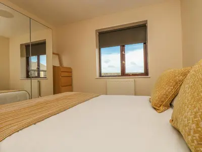 a bedroom with a bed and two windows at Seabreeze in Marazion