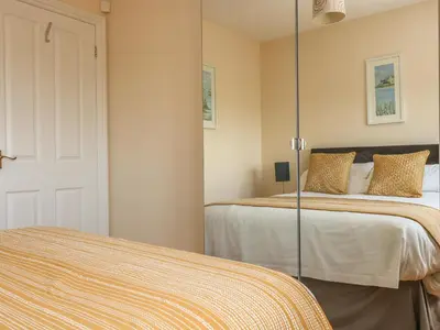 a bedroom with two beds and a mirror at Seabreeze in Marazion