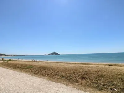 a sandy beach with people in the water at Sail Boats in Marazion