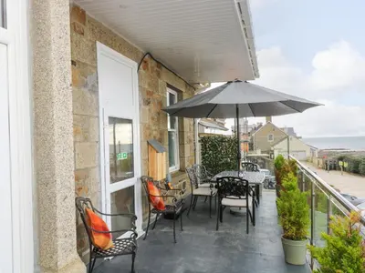 a balcony with tables and chairs and an umbrella at Mount View in Marazion