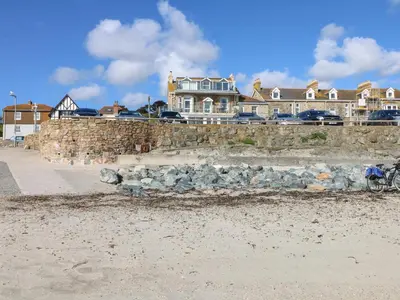 a stone wall on the beach with houses in the background at Mount View in Marazion