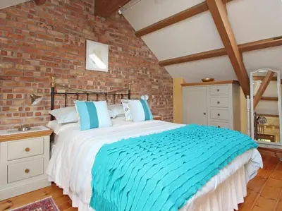a bedroom with a large bed with a brick wall at Summer House in Helston