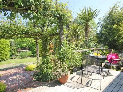 a table and chairs in a garden with a pergola at Summer House in Helston