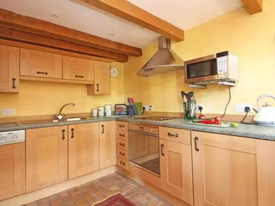 a kitchen with wooden cabinets and a microwave at Summer House in Helston