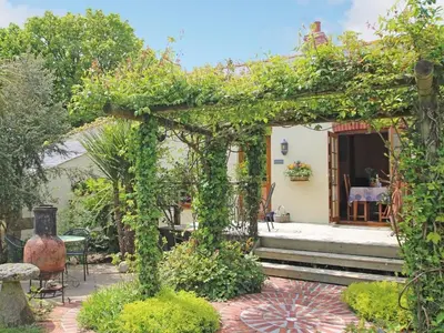 a pergola covered in ivy next to a house at Summer House in Helston