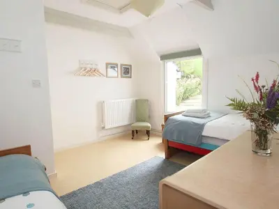 a bedroom with a bed and a chair and a window at White Duck Cottage in Hayle