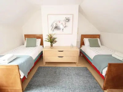 two twin beds in a attic room with a rug at White Duck Cottage in Hayle