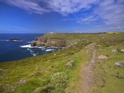 a path on a grassy hill next to the ocean at White Duck Cottage in Hayle