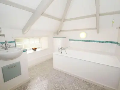 a white bathroom with a tub and a sink at White Duck Cottage in Hayle
