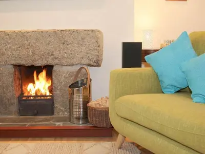 a living room with a fireplace and a green couch at White Duck Cottage in Hayle