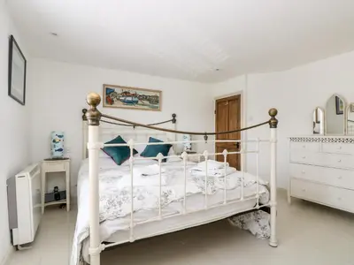 a bedroom with a white bed with blue pillows at Mallards in Pentewan