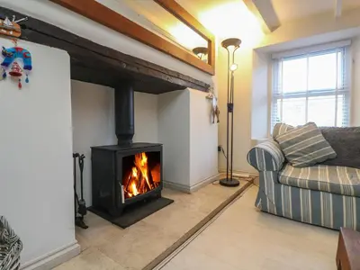 a living room with a fireplace and a couch at Mallards in Pentewan