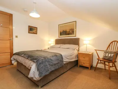 a bedroom with a bed and a chair at Ebenezer Cottage in Marazion