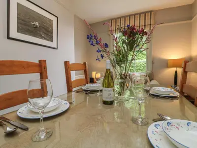 a dining room table with a bottle of wine and glasses at Penwarne Lodge in Budock Water