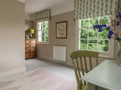 a dining room with a table and two windows at Penwarne Lodge in Budock Water