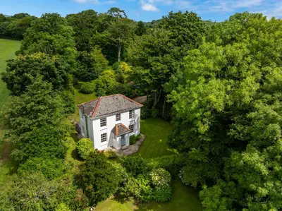 an aerial view of a white house in the woods at Penwarne Lodge in Budock Water