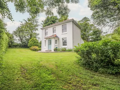 a white house with a large yard at Penwarne Lodge in Budock Water