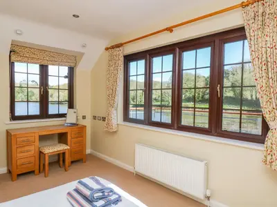 a bedroom with windows and a desk and a bed at Carne Mill in Helston