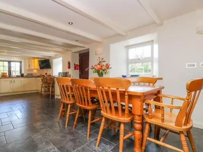 a kitchen and dining room with a wooden table and chairs at Carne Mill in Helston