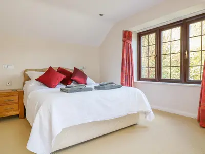 a bedroom with a bed with red pillows and a window at Carne Mill in Helston